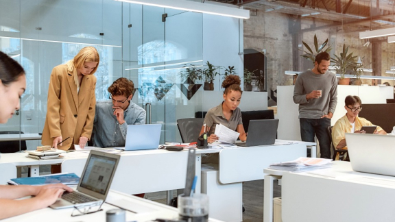 Employees working flexibly on laptops in a modern co-working space.