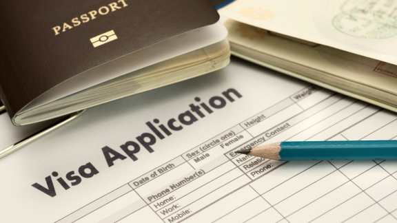 An English visa application form with a passport and a pencil for preparing essential visa and residency documents for an international move with DACHSER & KOLB.