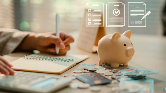 A piggy bank with cash, a credit card, and a calculator for planning finances, budget, and taxes during an international move with DACHSER & KOLB.