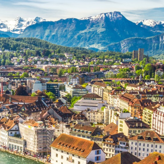 Panoramic view of the city of Lucerne with the Jesuit Church and the Swiss Alps in the background for an international move to Switzerland with DACHSER & KOLB.