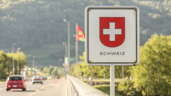 An official road sign with the Swiss coat of arms at a border crossing for customs clearance when moving to Switzerland with DACHSER & KOLB.
