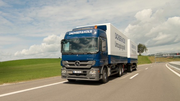 A modern moving truck with a trailer from the moving company DACHSER & KOLB on the road for secure transport during an international relocation.