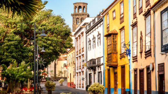 Historische Gasse mit bunten Kolonialhäusern und dem Kirchturm der Iglesia de la Concepción in La Laguna auf Teneriffa, passend zum Transport von Umzugskartons mit DACHSER & KOLB.