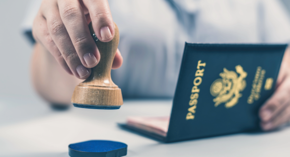 A passport is being stamped, symbolizing the formalities and organization of entry for relocation service expats.