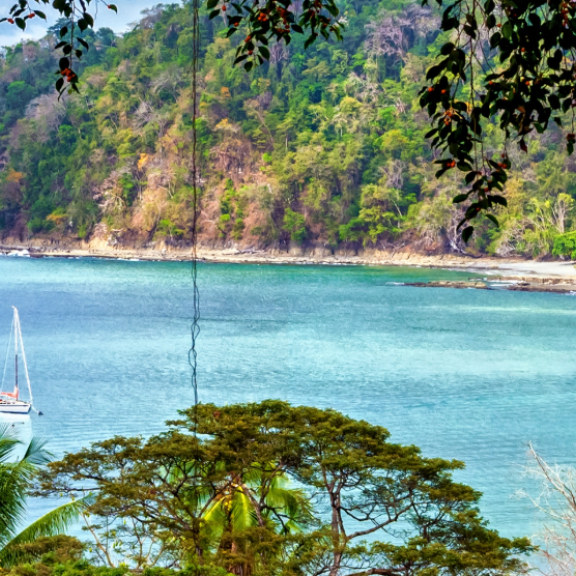 Tropische Bucht in Costa Rica mit türkisfarbenem Wasser, bewaldeter Küste und Segelboot