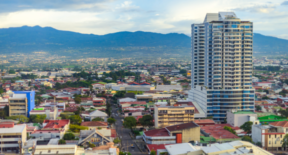 Stadtansicht in Costa Rica mit Hochhaus, Wohnvierteln und Bergen im Hintergrund“