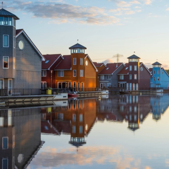 Bunte Häuser und Boote an einem Kanal in den Niederlanden bei ruhigem Abendlicht