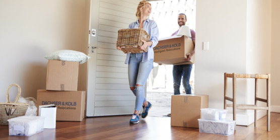 Couple carrying moving boxes and baskets into new home – tips and support in the moving guide