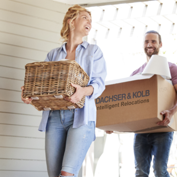 Couple carrying moving boxes and baskets into new home – tips and support in the moving guide
