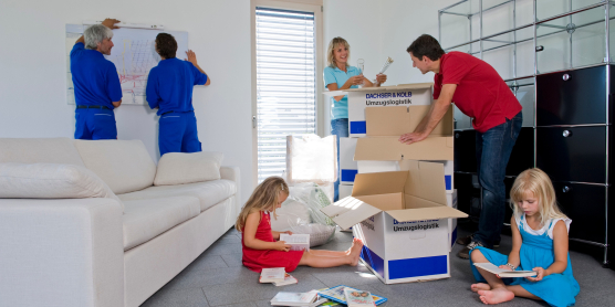 Umzugsdienstleistungen in Aktion: Möbel werden montiert, Kartons ausgepackt und Kinder genießen Bücher im neuen Zuhause.