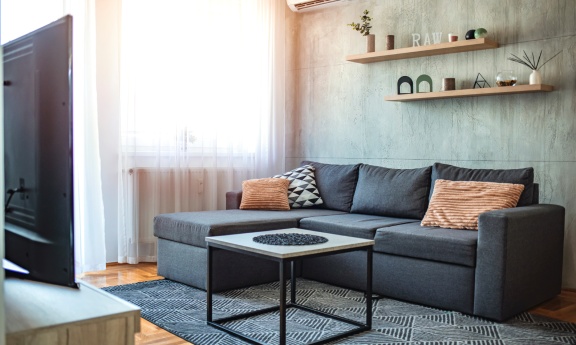 Modern eingerichtetes Wohnzimmer mit grauem Sofa – minimalistischer Wohntrend in Großstädten