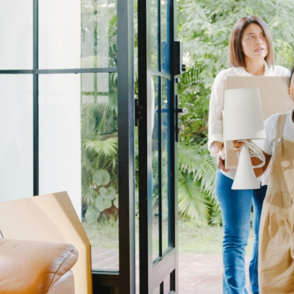Family carrying moving boxes into new home – symbolic image for practical living tips