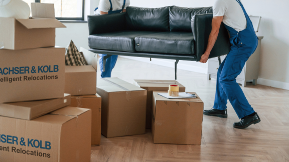 Movers carrying sofa and boxes – professional private relocation with DACHSER & KOLB