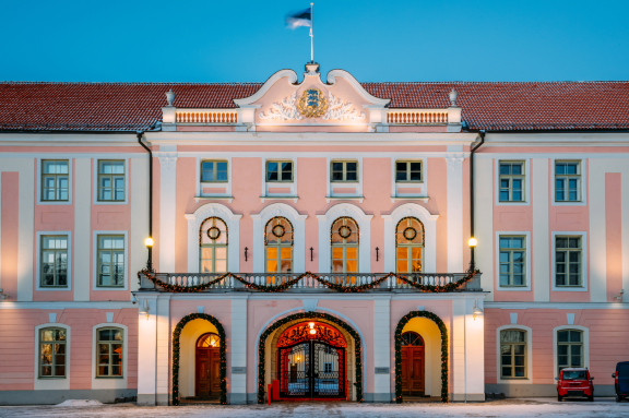 Historisches Gebäude in Estland mit Estlandflagge, rosa Fassade und beleuchtetem Eingang
