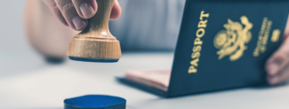 Hand mit Stempel vor Reisepass als Symbol für Einreise und Dokumente bei einem Umzug nach Estland