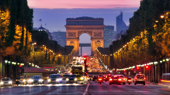 Arc de Triomphe in Paris bei Abenddämmerung mit Verkehr auf den Champs-Élysées