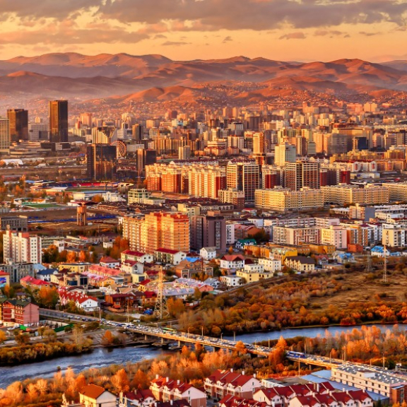 Panoramablick auf Ulaanbaatar in der Mongolei mit Skyline, Fluss und Bergen bei Sonnenuntergang