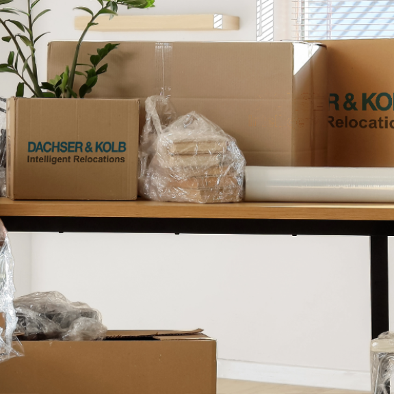 Verpackte Büromöbel und Umzugskartons mit DACHSER & KOLB Emballage in hellem Büro vor dem Firmenumzug