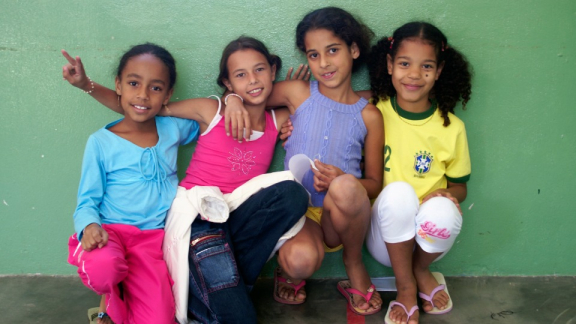 Vier Kinder sitzen lachend zusammen – Symbol für Bildung und Gemeinschaft bei Terre des hommes Deutschland.