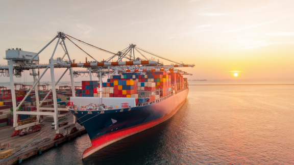 Containerschiff im Entladehafen bei Sonnenuntergang – Symbol für POD (Port of Discharge) im Seehandel.