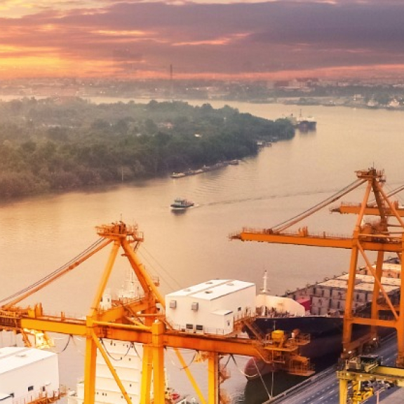 Containerhafen am Fluss bei Sonnenaufgang – Symbol für POE (Port of Entry) als zentraler Einfuhrhafen.