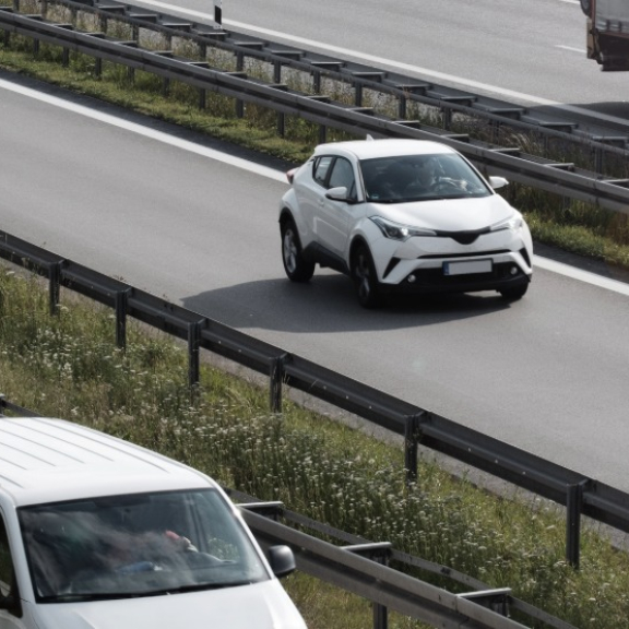 Blauer Lkw fährt auf Landstraße durch Berge – Symbol für Transportdauer beim Umzug.