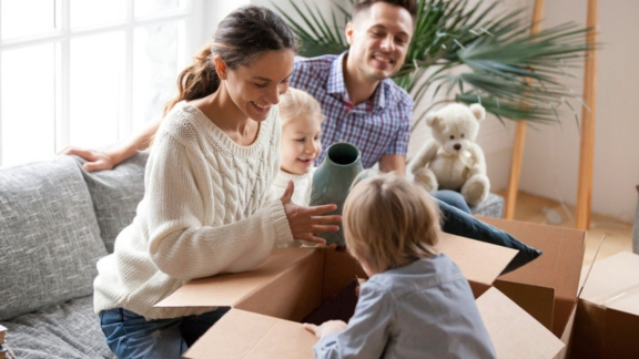 Familie mit Kind und Hund packt Umzugskartons – Symbol für stressfreie Organisation und Transportdauer beim Umzug.