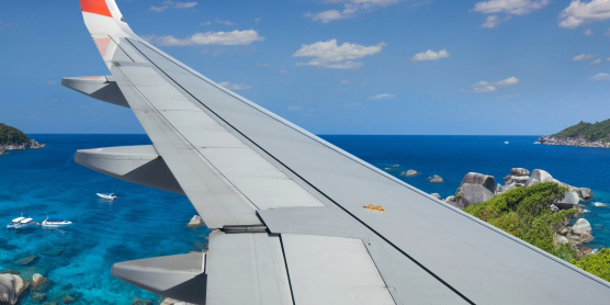 Blick aus dem Flugzeugfenster auf Thailands Küste – Symbolbild für Einreisebestimmungen und Zoll beim Thailand-Umzug.