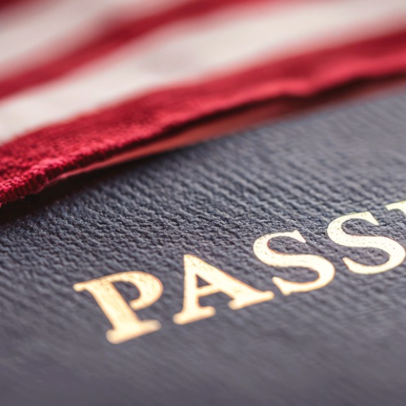 US-Pass unter der amerikanischen Flagge – Symbol für wichtige Visa- und Einreisedokumente beim Umzug in die USA.