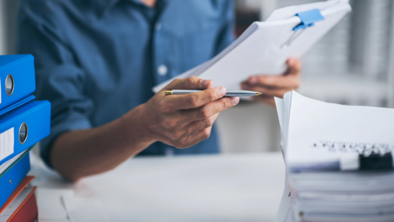 Mitarbeiter prüft Unterlagen und Aktenordner, um passende Fahrzeugtypen für Transport oder Umzug zu bestimmen