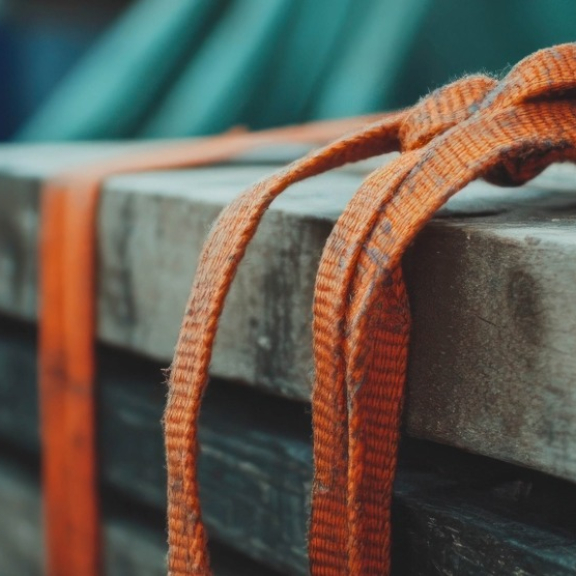 Orangene Spanngurte sichern Holzkiste für sicheren Transport auf der Ladefläche.