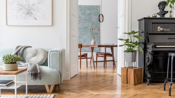 Helles Wohnzimmer mit Sofa, Esstisch und Klavier in einer stilvoll eingerichteten Altbauwohnung