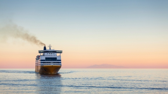 Havarie beim Seetransport: Brennendes Schiff auf See, beobachtet von einem Rettungsboot mit Menschen.