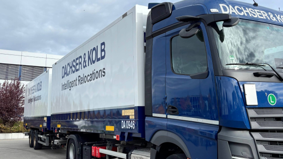 Havarie beim Seetransport: Brennendes Schiff auf See, beobachtet von einem Rettungsboot mit Menschen.