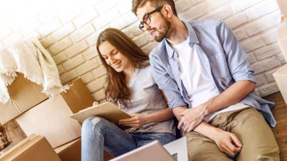 Paar plant Umzug zwischen Kartons mit Checkliste – Beratung zu Spezialverpackungen für empfindliche Gegenstände
