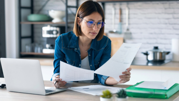 Person prüft Unterlagen am Laptop – Planung und Organisation für sicheren Transport im Wein-Karton