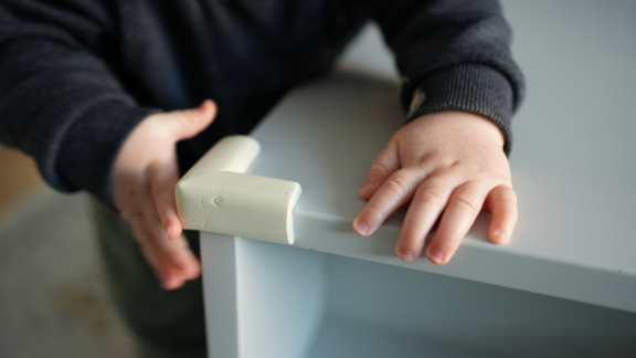 Eine Person sichert Tischkante mit Kantenschutz-Eckschutz, um Stöße und Verletzungen zu vermeiden