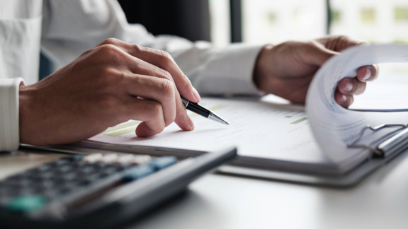 Person prüft Versanddokumente mit Stift – Planung und Abwicklung von Liftvan-Transporten