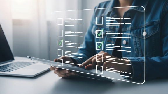 Person nutzt Tablet mit Checkliste am Laptop – TEU-Planung und Umzugsorganisation