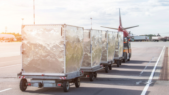 Luftfracht-Container auf Rollwagen am Flughafen-Vorfeld – Air Chargeable Weight als Basis für Frachtkosten