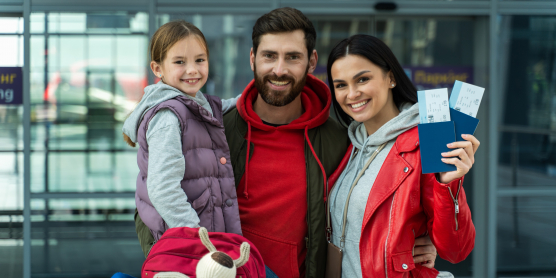 Lächelnde Familie am Flughafen mit Tickets – bereit für den Umzug mit Relocation Service für Privatpersonen