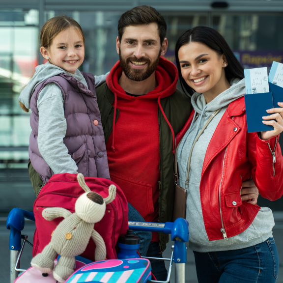 Smiling family at airport with tickets – ready to move with a relocation service for private individuals