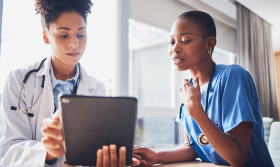 Zwei Ärztinnen, die konzentriert Gesundheitsdaten in einem Tablet ansehen